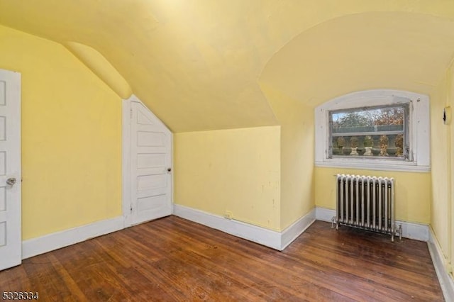 additional living space with dark hardwood / wood-style flooring, radiator heating unit, and vaulted ceiling