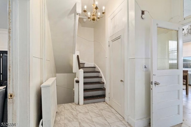 staircase with an inviting chandelier