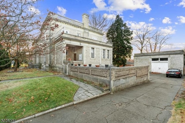 neoclassical / greek revival house with a garage, an outbuilding, and a front lawn