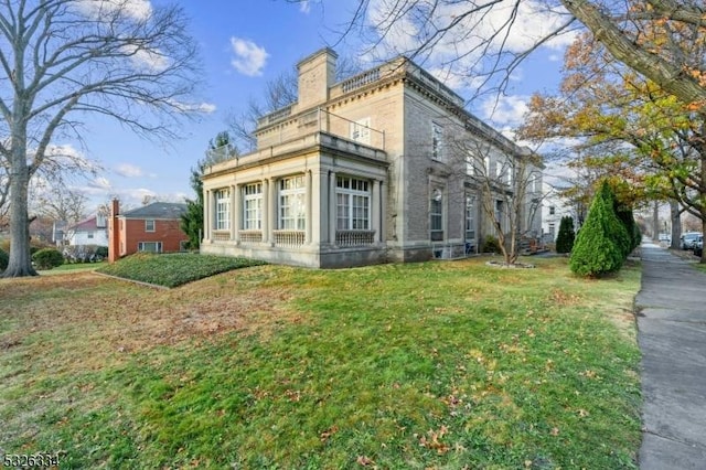 view of side of property with a yard and a balcony