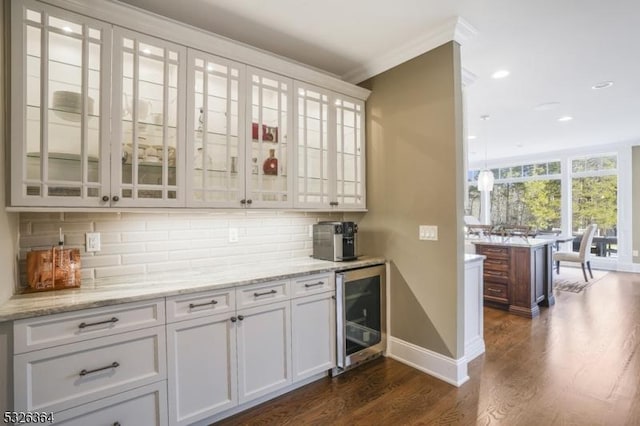 bar with wine cooler, light stone counters, dark hardwood / wood-style floors, backsplash, and white cabinets