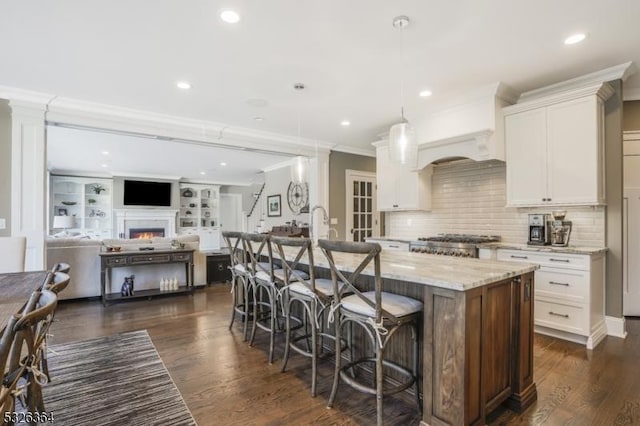 kitchen featuring light stone countertops, a kitchen bar, white cabinetry, and an island with sink