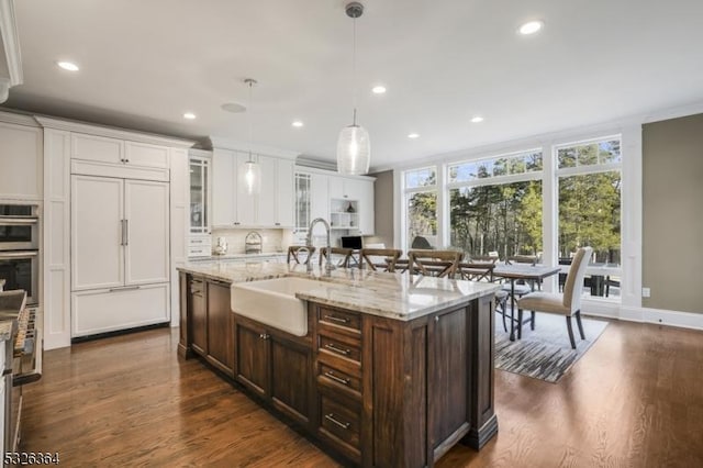 kitchen featuring sink, paneled refrigerator, dark hardwood / wood-style flooring, an island with sink, and pendant lighting