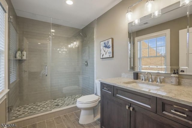 bathroom with vanity, toilet, and a shower with door