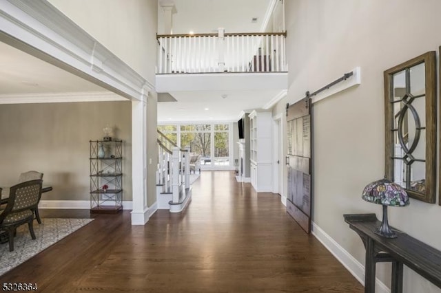 foyer entrance featuring a barn door, ornamental molding, and dark wood-type flooring