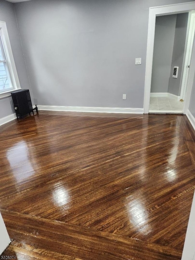 unfurnished room with radiator and dark hardwood / wood-style floors