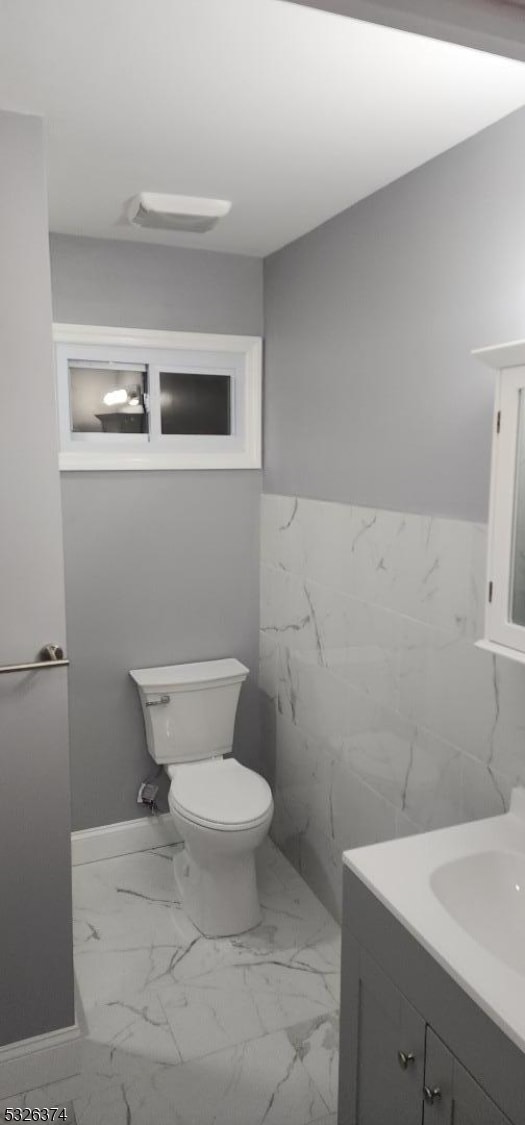 bathroom with vanity, tile walls, and toilet