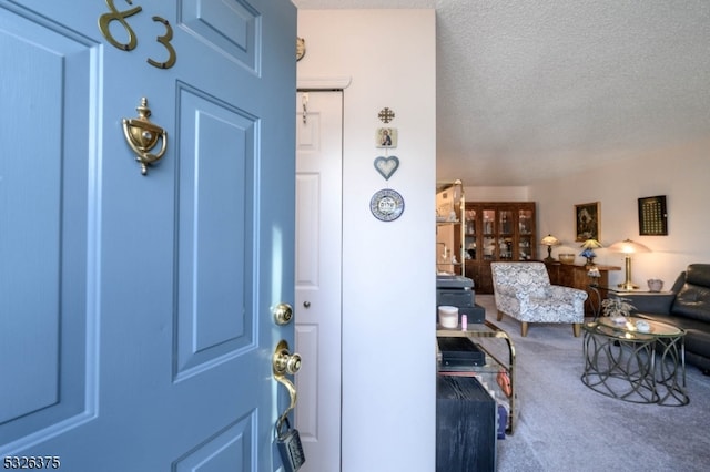 carpeted foyer entrance featuring a textured ceiling