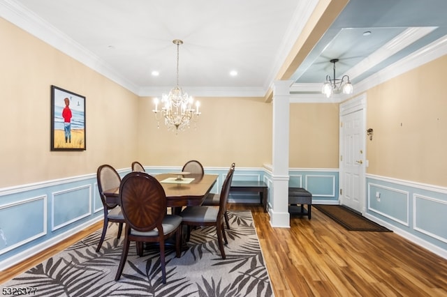 dining room featuring a chandelier, hardwood / wood-style floors, ornate columns, and ornamental molding