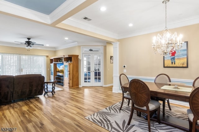 dining space featuring french doors, ceiling fan with notable chandelier, hardwood / wood-style flooring, ornamental molding, and ornate columns