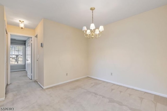 empty room featuring a chandelier, light colored carpet, and baseboards