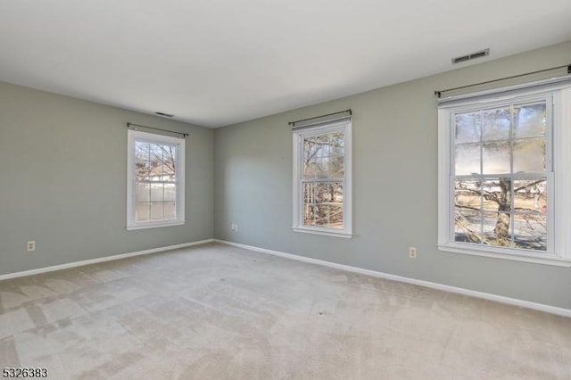 unfurnished room with visible vents, light colored carpet, and a healthy amount of sunlight