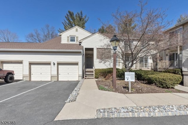 view of property with an attached garage, driveway, and a shingled roof