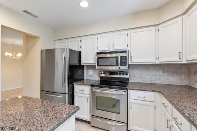 kitchen featuring visible vents, stainless steel appliances, dark stone counters, white cabinets, and decorative backsplash