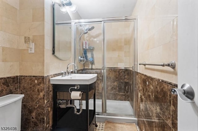 bathroom with sink, tile walls, tile patterned flooring, toilet, and a shower with shower door