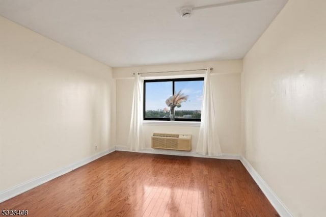 unfurnished room featuring a wall mounted air conditioner and hardwood / wood-style floors