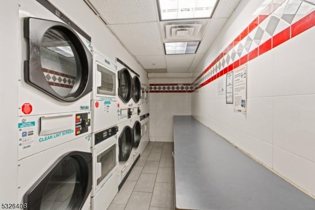 laundry area with stacked washer and dryer and light tile patterned flooring