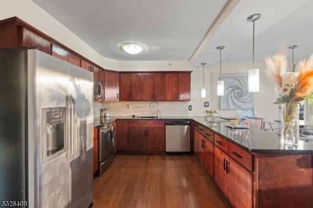 kitchen with backsplash, hanging light fixtures, dark hardwood / wood-style floors, kitchen peninsula, and stainless steel appliances