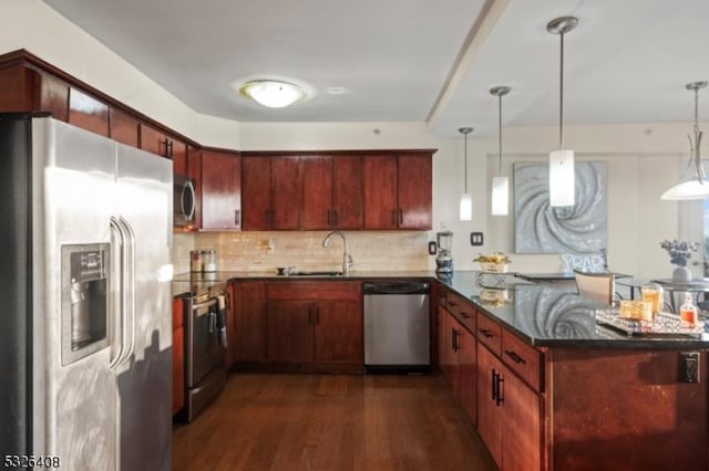 kitchen featuring pendant lighting, sink, dark hardwood / wood-style floors, kitchen peninsula, and stainless steel appliances