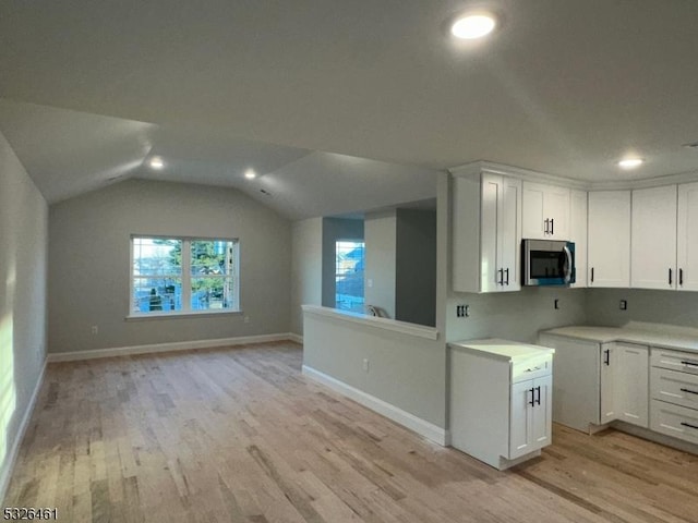 kitchen featuring lofted ceiling, light wood-type flooring, and white cabinetry