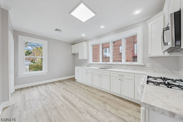 kitchen with white cabinets, crown molding, sink, and light hardwood / wood-style flooring