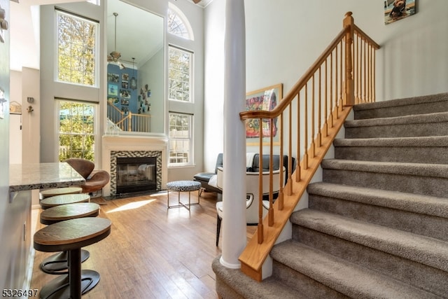 staircase with a high ceiling, hardwood / wood-style floors, and a healthy amount of sunlight