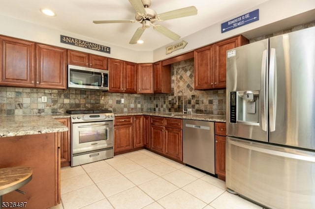 kitchen with sink, backsplash, light tile patterned floors, and stainless steel appliances