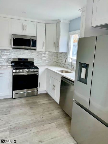 kitchen with white cabinets, decorative backsplash, stainless steel appliances, and sink