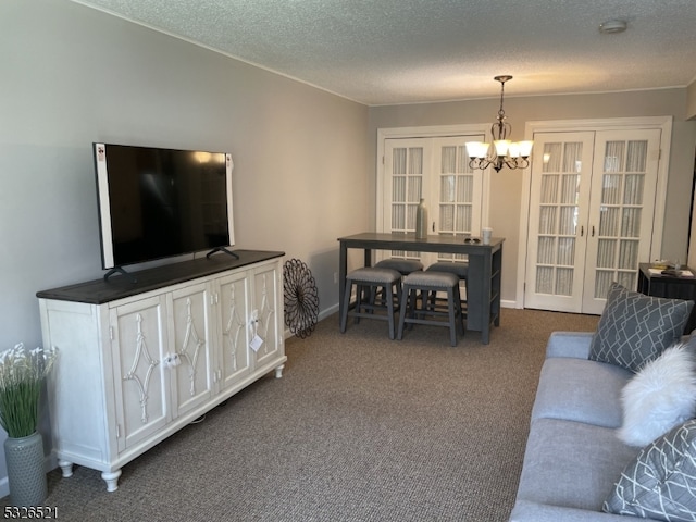 living room featuring french doors, dark carpet, a textured ceiling, and a notable chandelier