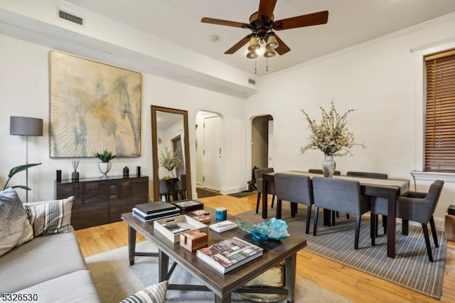 living room featuring ceiling fan, wood-type flooring, and crown molding