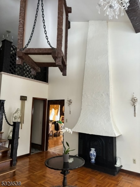 living room featuring parquet flooring, a chandelier, a towering ceiling, and a fireplace