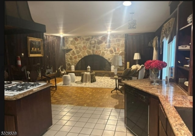 kitchen with light tile patterned flooring, dishwasher, white gas cooktop, and a stone fireplace