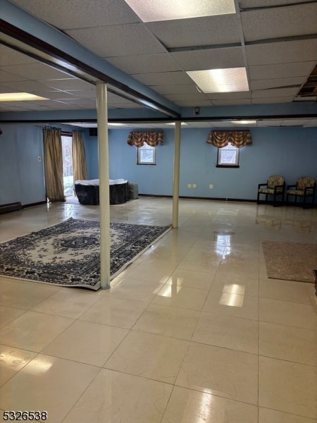 basement with light tile patterned floors and a paneled ceiling