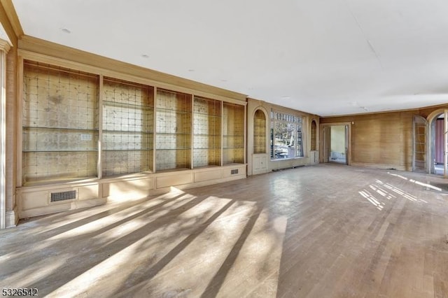 unfurnished living room featuring wood-type flooring, built in shelves, and wood walls