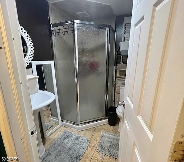 bathroom with wood-type flooring, toilet, and walk in shower