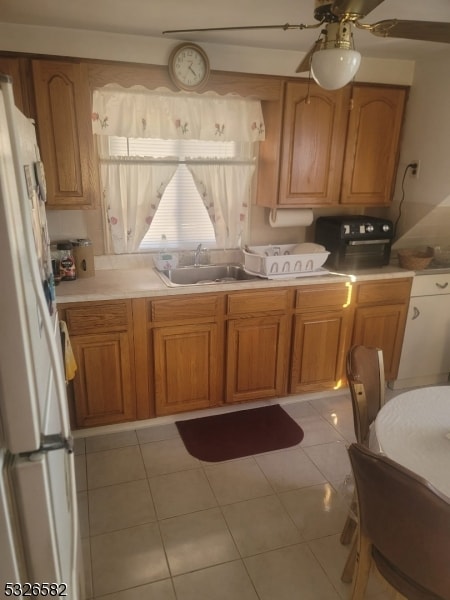 kitchen with ceiling fan, white refrigerator, light tile patterned floors, and sink