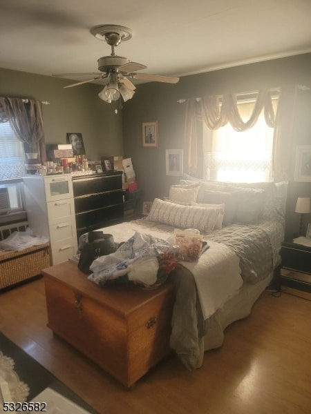 bedroom featuring multiple windows, hardwood / wood-style floors, and ceiling fan