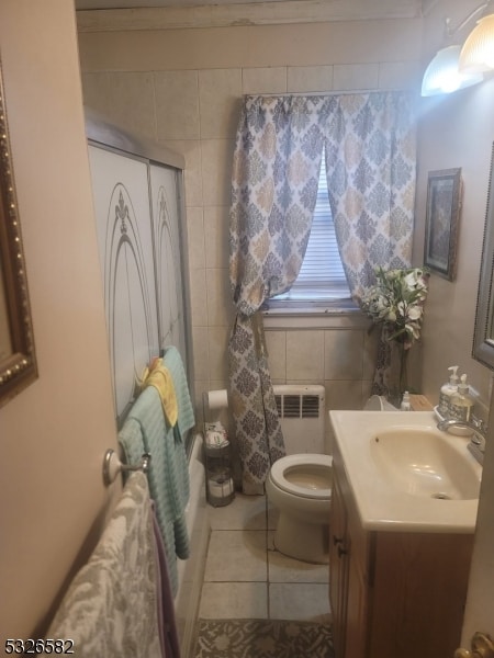 bathroom with tile patterned floors, vanity, tile walls, radiator heating unit, and toilet