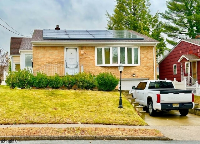 view of front of home featuring a front yard, a garage, and solar panels