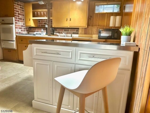 kitchen with white oven, light tile patterned floors, and white cabinets