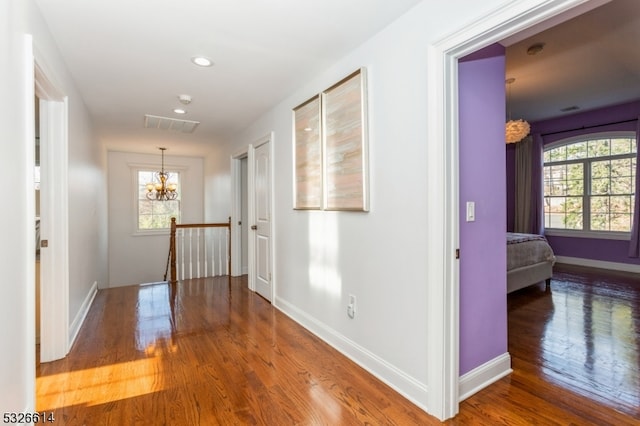 hall featuring hardwood / wood-style floors, plenty of natural light, and a notable chandelier