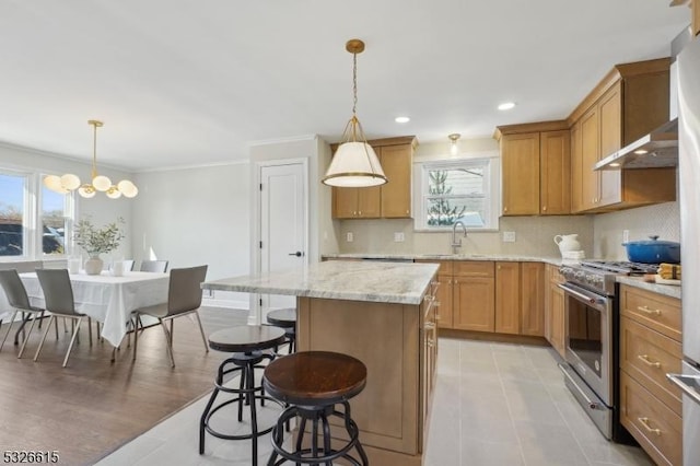 kitchen featuring a kitchen island, stainless steel range with gas cooktop, pendant lighting, sink, and decorative backsplash