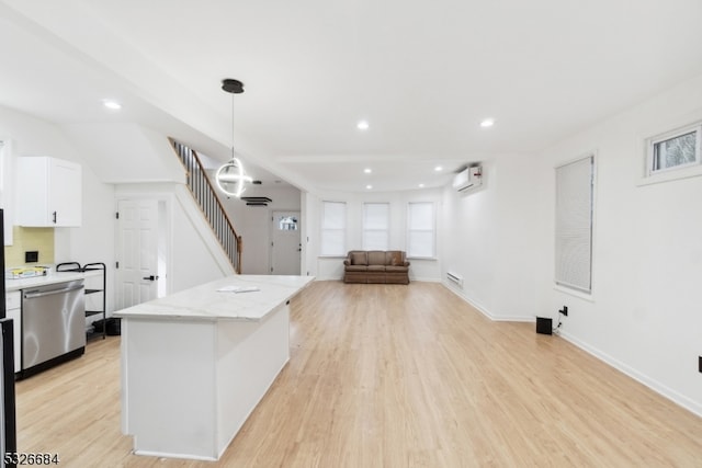 kitchen featuring light wood-type flooring, white cabinets, a wall mounted AC, pendant lighting, and dishwasher