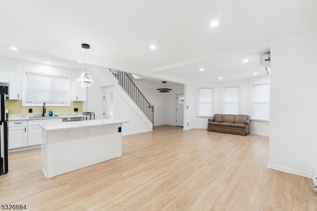 kitchen with white cabinetry, light hardwood / wood-style flooring, pendant lighting, and sink