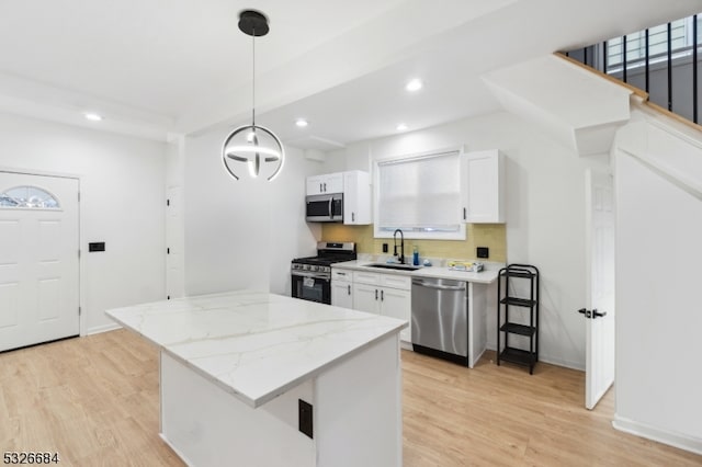 kitchen featuring white cabinetry, sink, stainless steel appliances, and decorative light fixtures