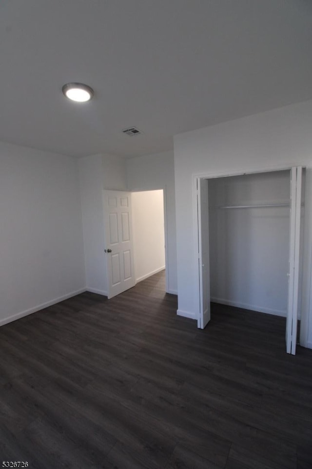 unfurnished bedroom featuring dark wood-type flooring and a closet