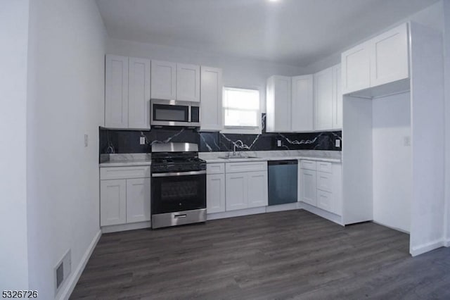 kitchen featuring tasteful backsplash, stainless steel appliances, dark wood-type flooring, sink, and white cabinetry