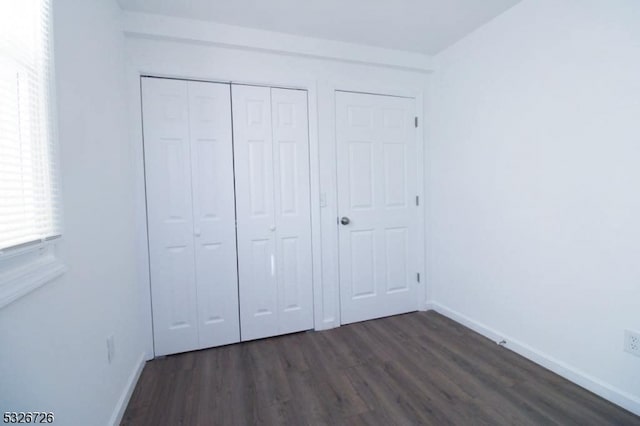 unfurnished bedroom featuring dark hardwood / wood-style floors and a closet