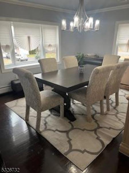 dining space with crown molding, an inviting chandelier, and hardwood / wood-style flooring