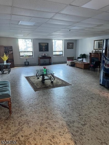 carpeted living room with a drop ceiling and a healthy amount of sunlight